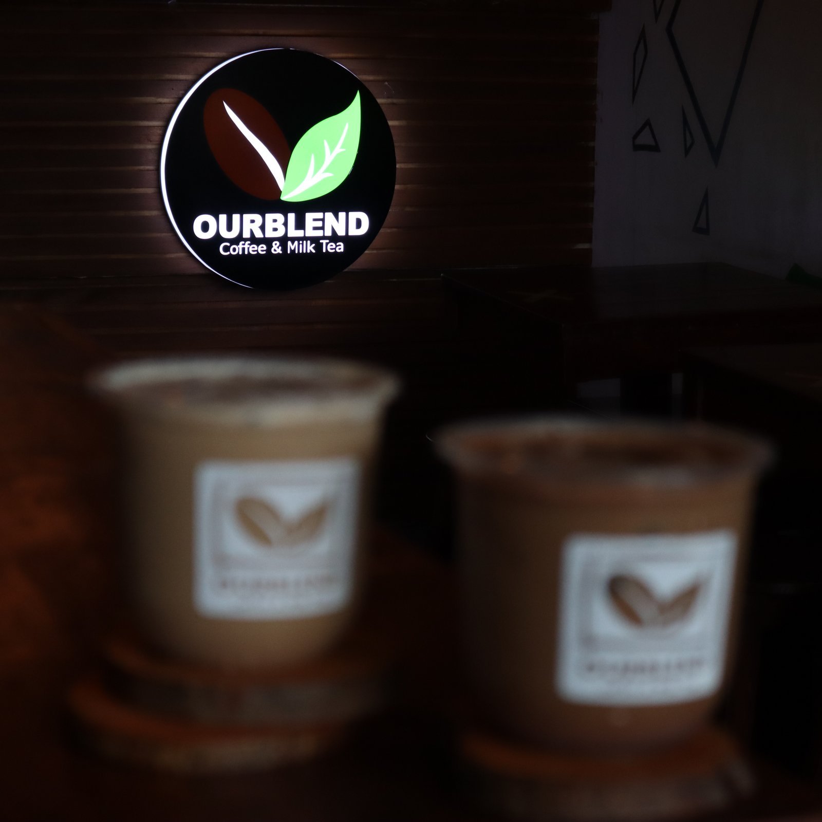 Lit circular OURBLEND wall sign with café cups